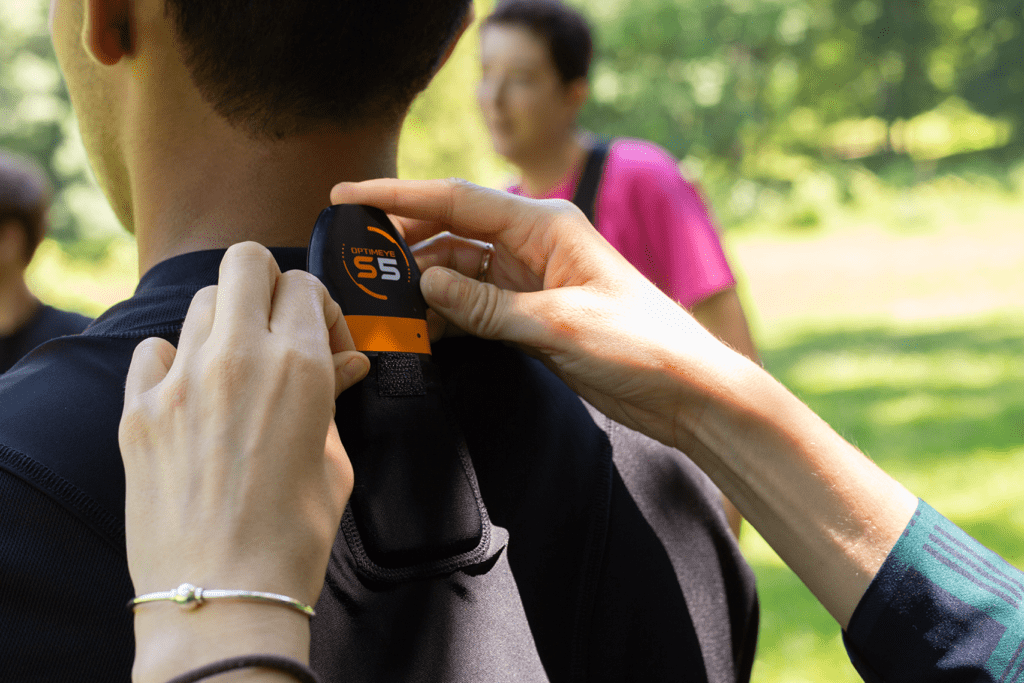 Individual afixing a wearable performance tracking device to an athlete