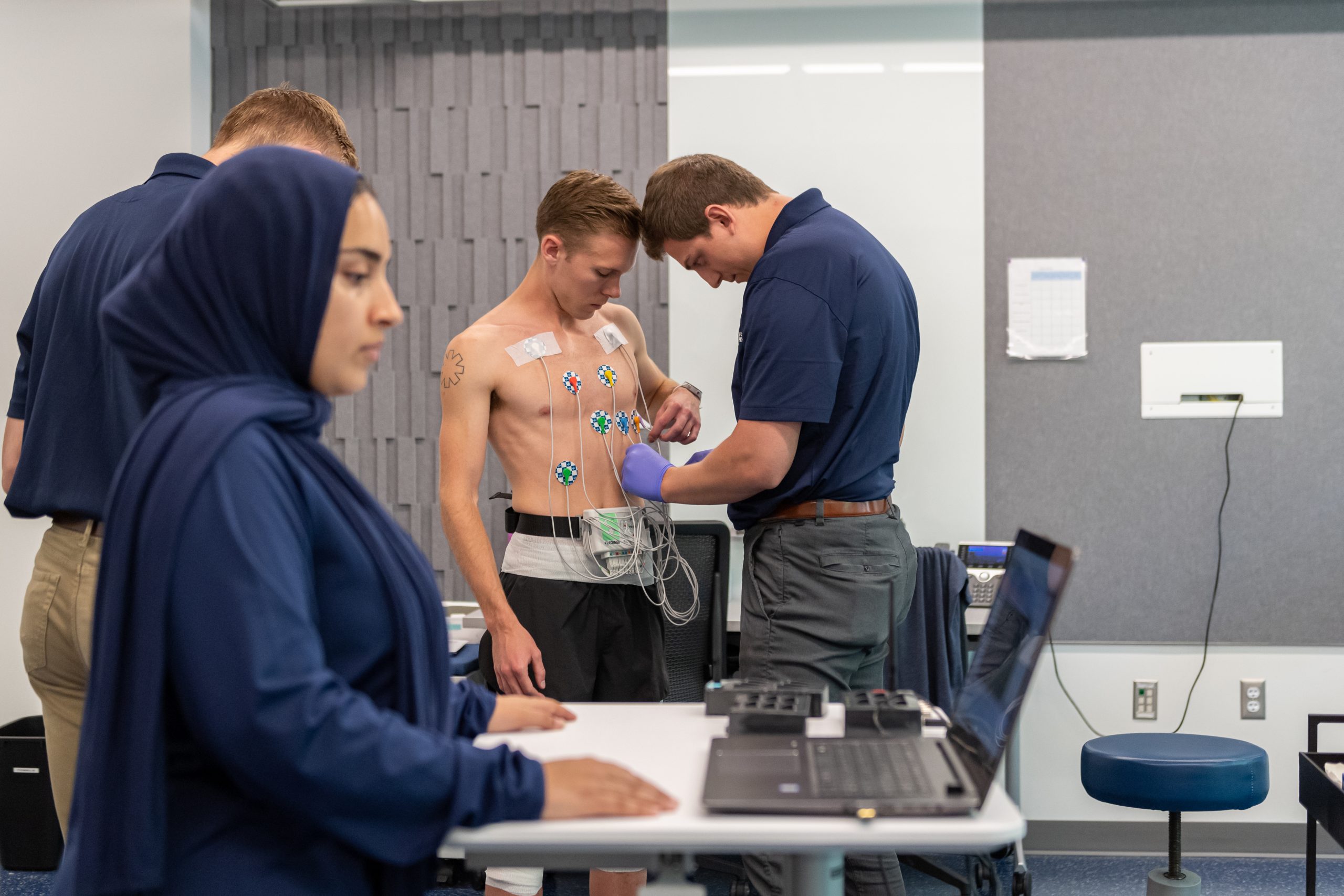 Students connecting vital tracking devices to an athlete for the Kineseology treadmill study.